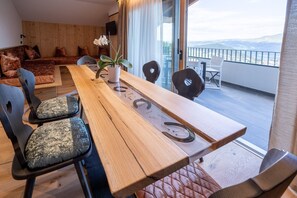 Una mesa de comedor de madera con sillas, una orquídea en maceta y vistas al exterior.