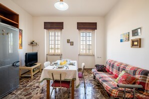 Un espace de vie compact comprenant un coin repas, un canapé, un téléviseur et un réfrigérateur.