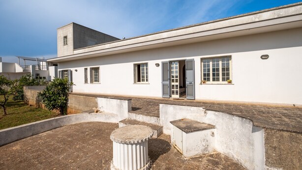Ein modernes Gebäude mit flachem Dach, großen Fenstern und einem kleinen Balkon.