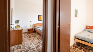 Ein Schlafzimmer mit Bett, Nachttisch, Lampe und einem kleinen Schrank.