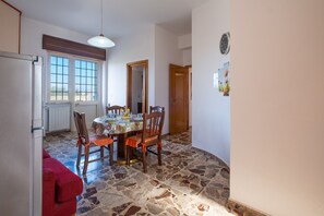 Un coin repas avec une table dressée pour quatre personnes, un canapé rouge et un sol en pierre.