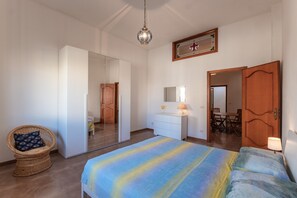 A bedroom with a bed, a wardrobe, a mirror, a dining table, and a chair.