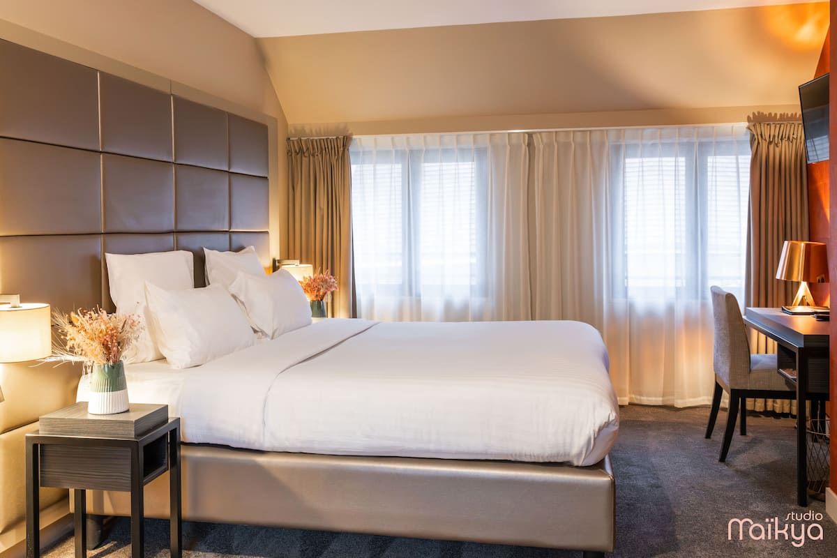 A hotel room with a large bed, a desk, and a chair.