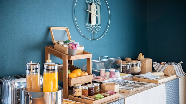 Un bufé de desayuno con diversas opciones de comida, un tostador y una cesta de frutas.