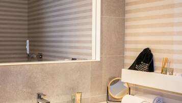 A bathroom with a large mirror, a sink, toiletries, and a towel rack.