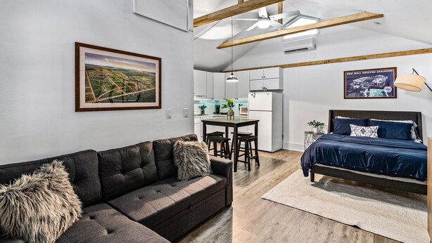Un moderno apartamento estilo loft con cama en altillo, sofá, zona de comedor y cocina.