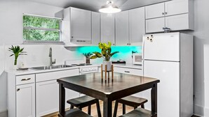 Una cocina moderna con armarios blancos, una mesa de comedor de madera y un centro de mesa con planta verde.