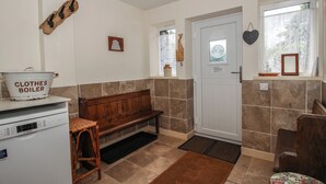 Une cuisine compacte équipée d’un appareil Bosch, d’un banc en bois, d’une cuve à linge et d’une porte avec une fenêtre.