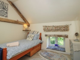 Un dormitorio con una cama de madera, una ventana con vistas, una mesita con un espejo y un estante montado en la pared.