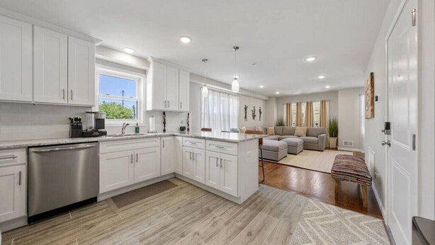 A modern kitchen with white cabinetry, a stainless steel dishwasher, and a large island.