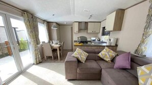 A compact living space with a sofa, a dining area, and a kitchenette. - Impeccable 3-bed Cabin in Tattershall, UK (Lincoln)