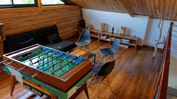 Una habitación acogedora con mesa de fútbol, un sofá y dos sillones.