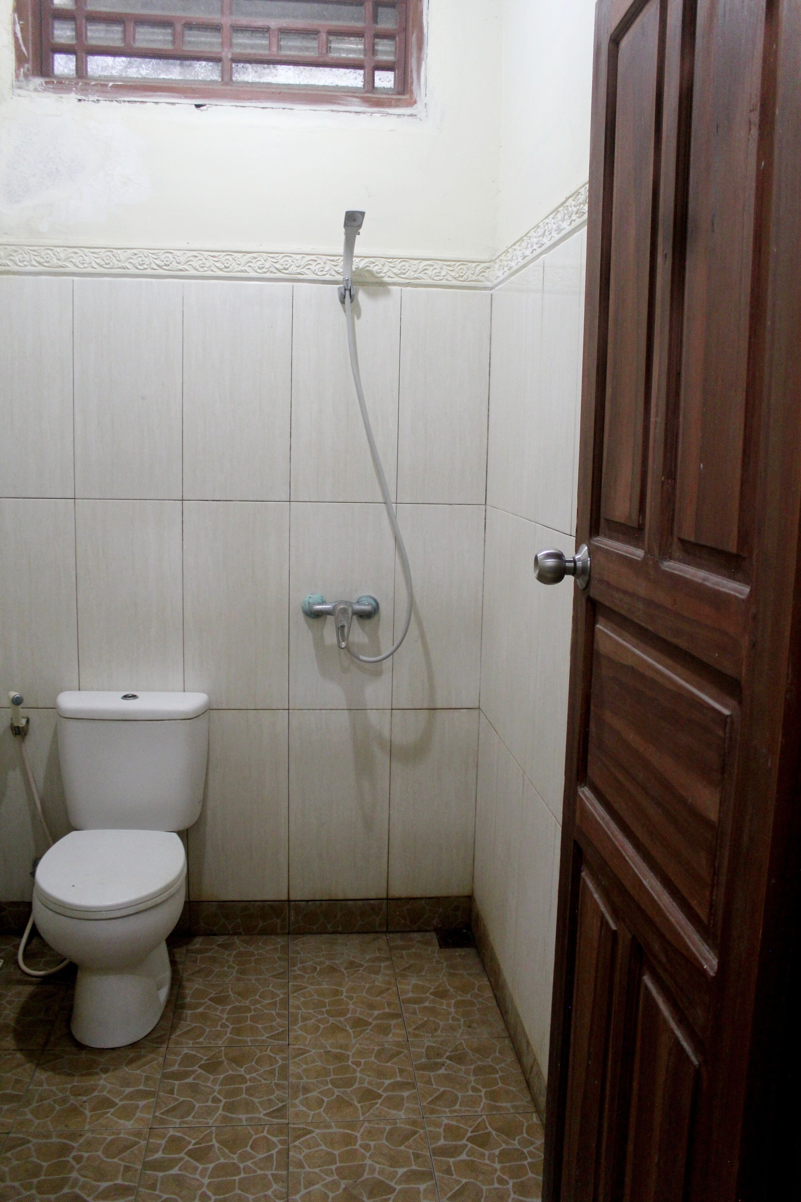 A small bathroom with a toilet, a shower, and a wooden door.