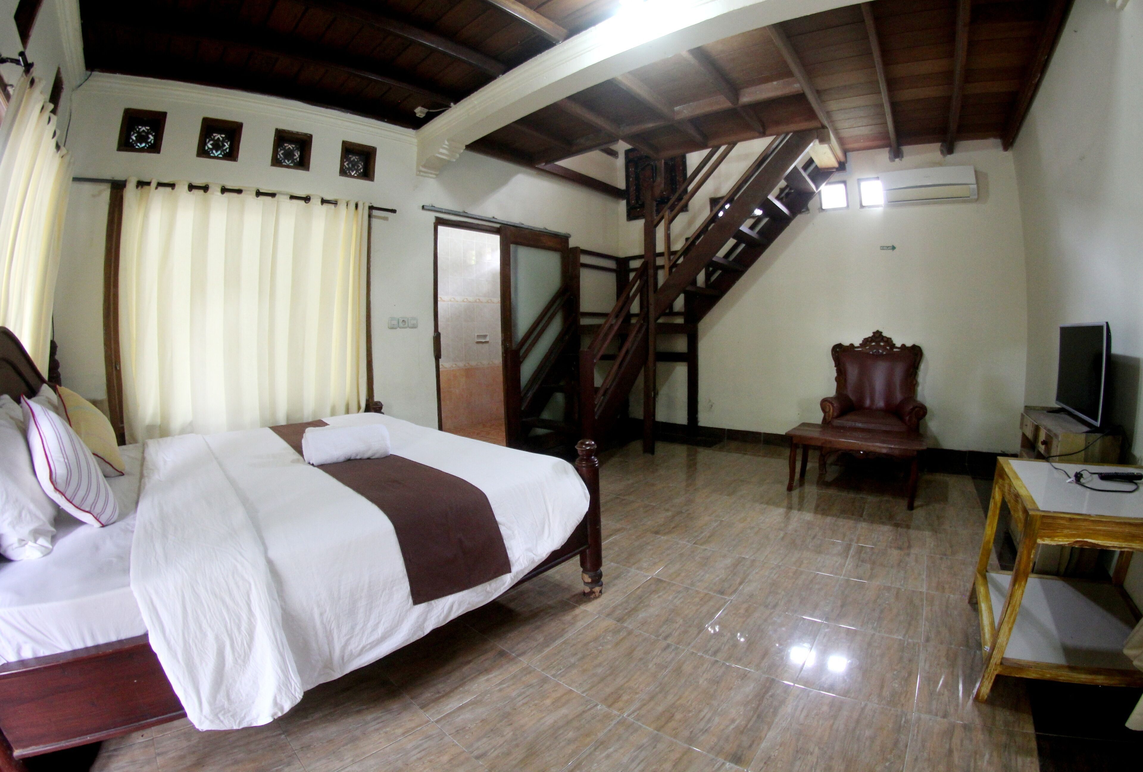 A bedroom with a bed, a chair, a desk, a television, and a staircase.