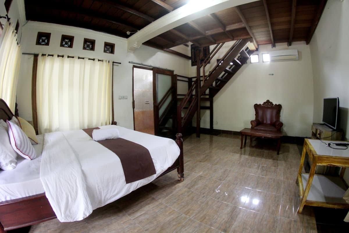 Ein Schlafzimmer mit einem Bett, einem Sessel, einem Schreibtisch, einem Fernseher und einer Treppe.
