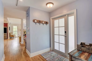 A hallway with a wooden floor, a patterned rug, a door with frosted glass panels, and a wall-mounted decorative item.