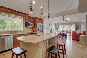 A spacious kitchen with a large island, bar stools, and a dining area with a red sofa and chairs.