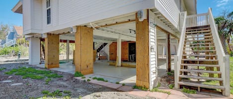 A two-story house with a covered porch supported by wooden posts, a wooden staircase, and a visible interior staircase.