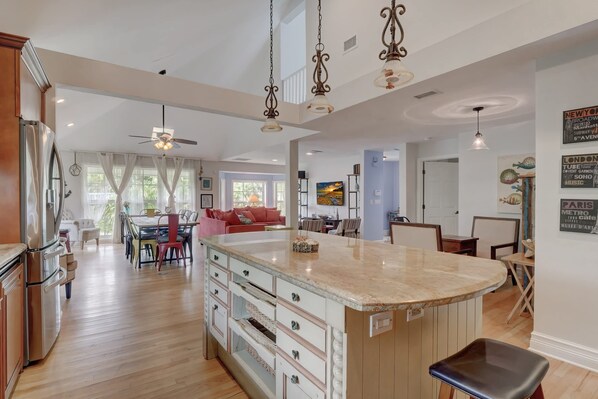 A spacious kitchen with a central island, wooden cabinets, and a ceiling fan.