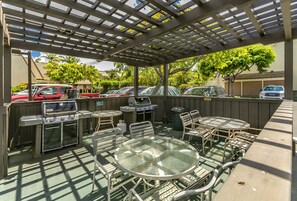 Une terrasse extérieure dotée d’une pergola, d’un barbecue et d’une table avec des chaises.