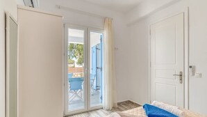 A hotel room with a bed, a door, and a sliding glass door leading to an outdoor area with a pool and chairs.
