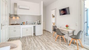 A modern kitchen with white cabinets, a built-in stove, and a microwave. There is a dining area with a table and chairs.