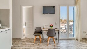 Una cucina moderna con frigorifero integrato, un'area pranzo con due sedie, un tavolo con un vaso di fiori e un televisore a parete.