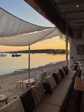 A seaside restaurant with outdoor seating, a view of the water, and a sunset. - Paros Seaside Splendor - Apollo's Poolside Retreat (Aliki)