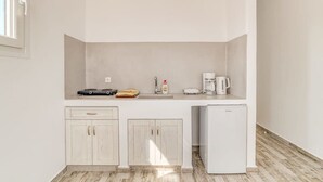 Een kleine keuken met een koelkast, een koffiezetapparaat en een magnetron.