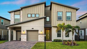 A modern two-story house with a stone facade, a garage, and a well-maintained lawn. - The Sea Renity | Relax & Rejuvenate in This Picturesque Retreat, Mins From Beach (Melbourne Beach)