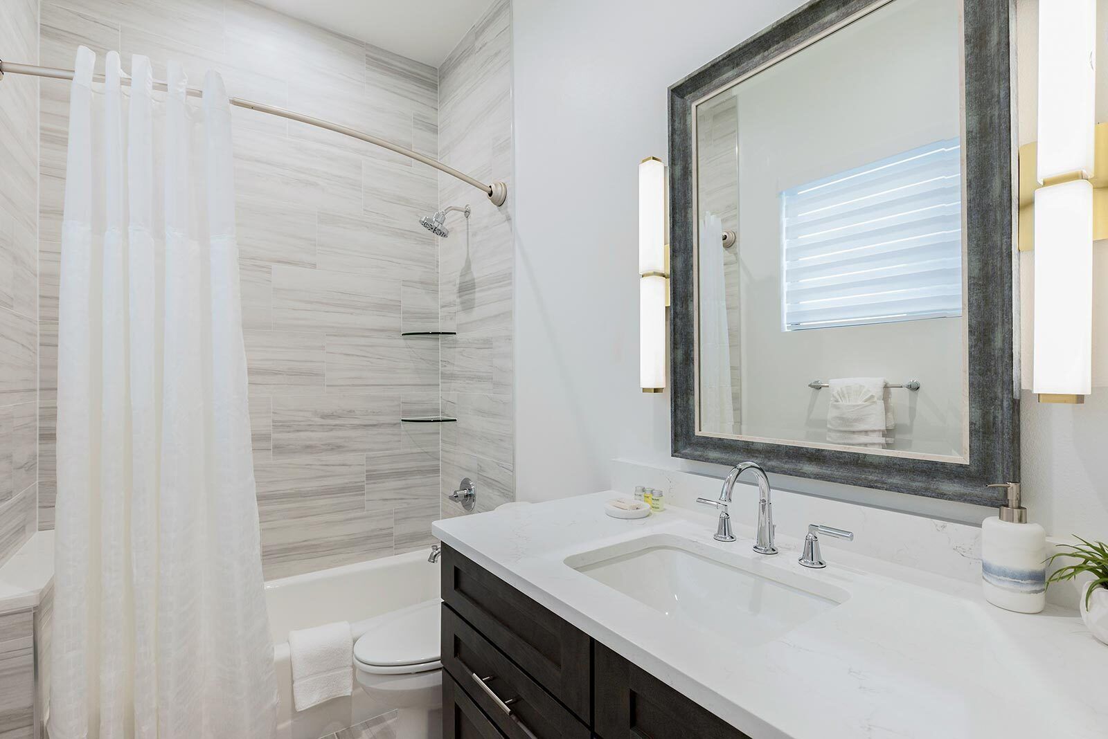 A modern bathroom with a shower, toilet, and vanity with a large mirror.