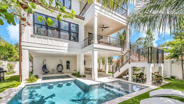 A modern two-story house with a swimming pool, outdoor seating, and a balcony.