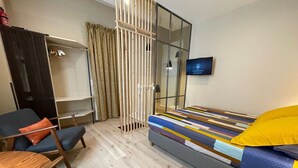 A modern hotel room with a bed, a desk, a chair, a wardrobe, and a television. - Quartier Voltaire - Rue Pache (Paris)