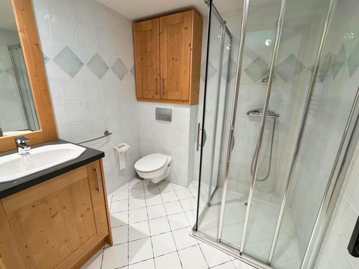 Ein Badezimmer mit Holzwaschtisch, Toilette und Duschkabine.