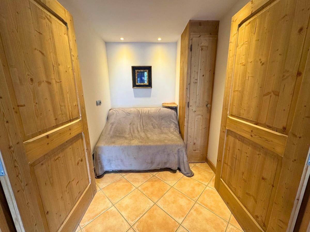 Un dormitorio con cama, armario de madera y un cuadro en la pared.