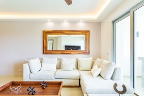 A modern living room with a sectional sofa, a wooden coffee table, and a large mirror on the wall.