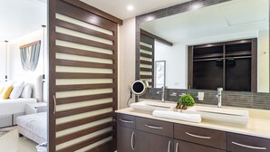 Une salle de bain moderne avec un grand miroir, un lambris en bois foncé et un lavabo blanc.