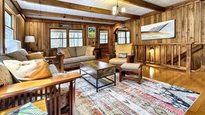 A cozy cabin interior with a sofa, armchairs, a wooden coffee table, and a rug. - Creekside,firepit,wood stove,family&dog friendly,covered deck dining (Scaly Mountain)