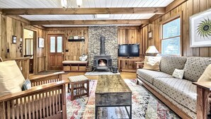A cozy living room with a stone fireplace, wooden furniture, and a television. - Creekside,firepit,wood stove,family&dog friendly,covered deck dining (Scaly Mountain)