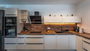 Una cocina moderna con electrodomésticos integrados, encimera de madera y armarios blancos.