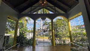 A covered patio with a view of a garden and a building in the background. - Yancey Largo Villa Perfect Jamaica Ironshore Getaway w Private Pool and Onsite Staff Services by RedAwning (Montego Bay)
