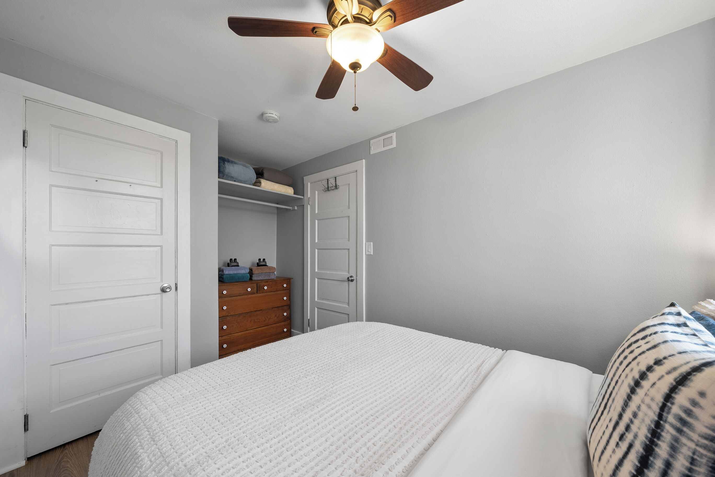 Ein Schlafzimmer mit Bett, Deckenventilator und Kleiderschrank.