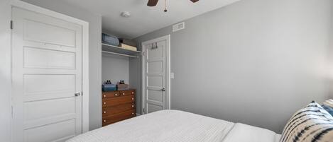 Ein Schlafzimmer mit Bett, Deckenventilator und Kleiderschrank.