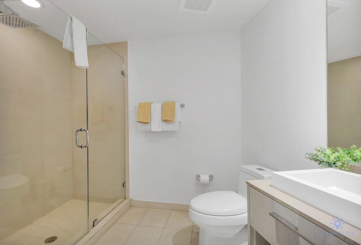 Une salle de bain moderne avec une douche à parois de verre, des toilettes blanches et une grande baignoire.