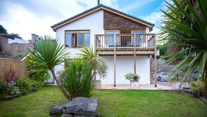 A two-story house with a balcony, a stone facade, and a well-maintained garden with various plants. - Bayview House - 4 Bedroom - Saundersfoot (Saundersfoot)