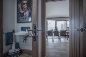 A bathroom with a sink, toilet paper, and a poster on the wall.