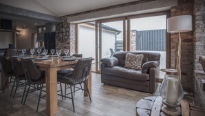 A dining area with a wooden table set for six, a leather sofa, and a rustic lamp. - Bayview House - 4 Bedroom - Saundersfoot (Saundersfoot)