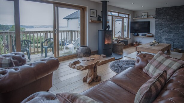 A cozy living room with a fireplace, leather sofas, and a wooden coffee table. - Bayview House - 4 Bedroom - Saundersfoot (Saundersfoot)