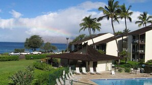 A hotel with a pool, palm trees, and a view of the ocean.