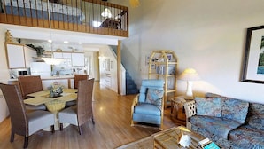 A spacious living area with a dining table, chairs, a sofa, and a staircase leading to an upper level.